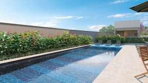 Piscina tipo raia com deck e área de lazer ao ar livre do condomínio